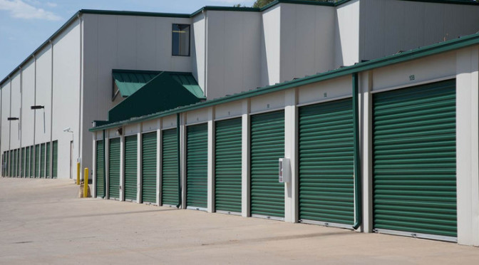Exterior view of facility with large outdoor storage units with green doors in a clean environment