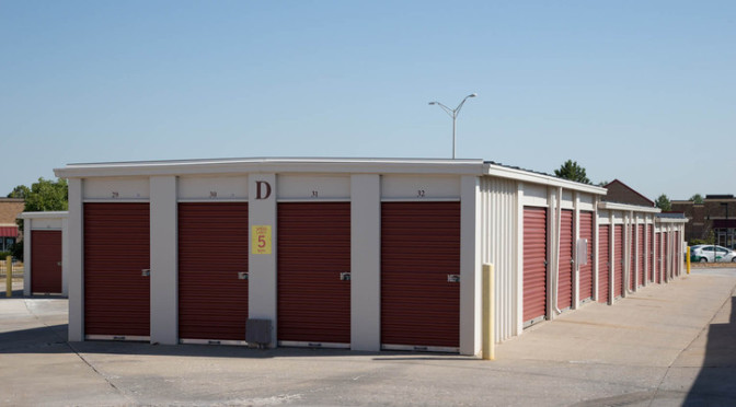 A row of small, outdoor storage units with red doors in a clean environment