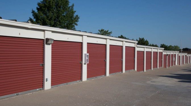 A row of outdoor storage units with red doors in a clean environment