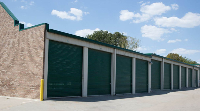 Row of outdoor storage units with green doors in a clean environment