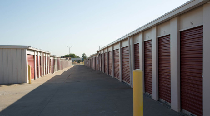 A long row of outdoors storage units with red doors in a clean environment